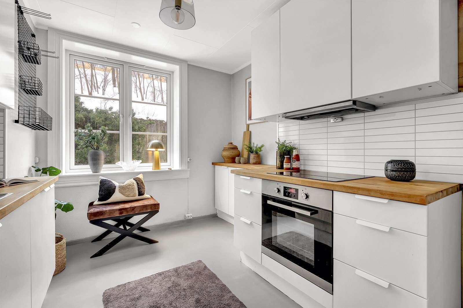 Tidløs innredning med lyse, glatte fronter og heltre benkeplate. Det er flislagt på veggen over kjøkkenbenken. Galleribilde