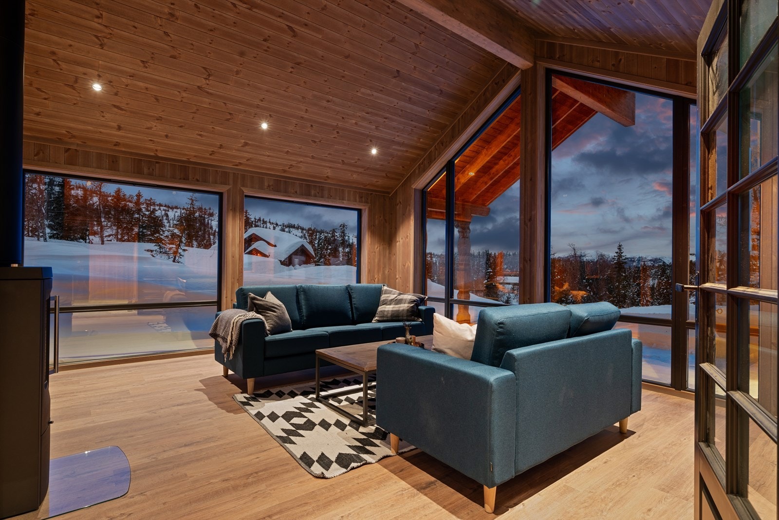 Stuen har store vindusflater som slipper inn rikelig med dagslys. Downlights i røstet himling skaper en følelse av å være ett med naturen, og du kan nyte utsikten uansett hvor du befinner deg i rommet Galleribilde