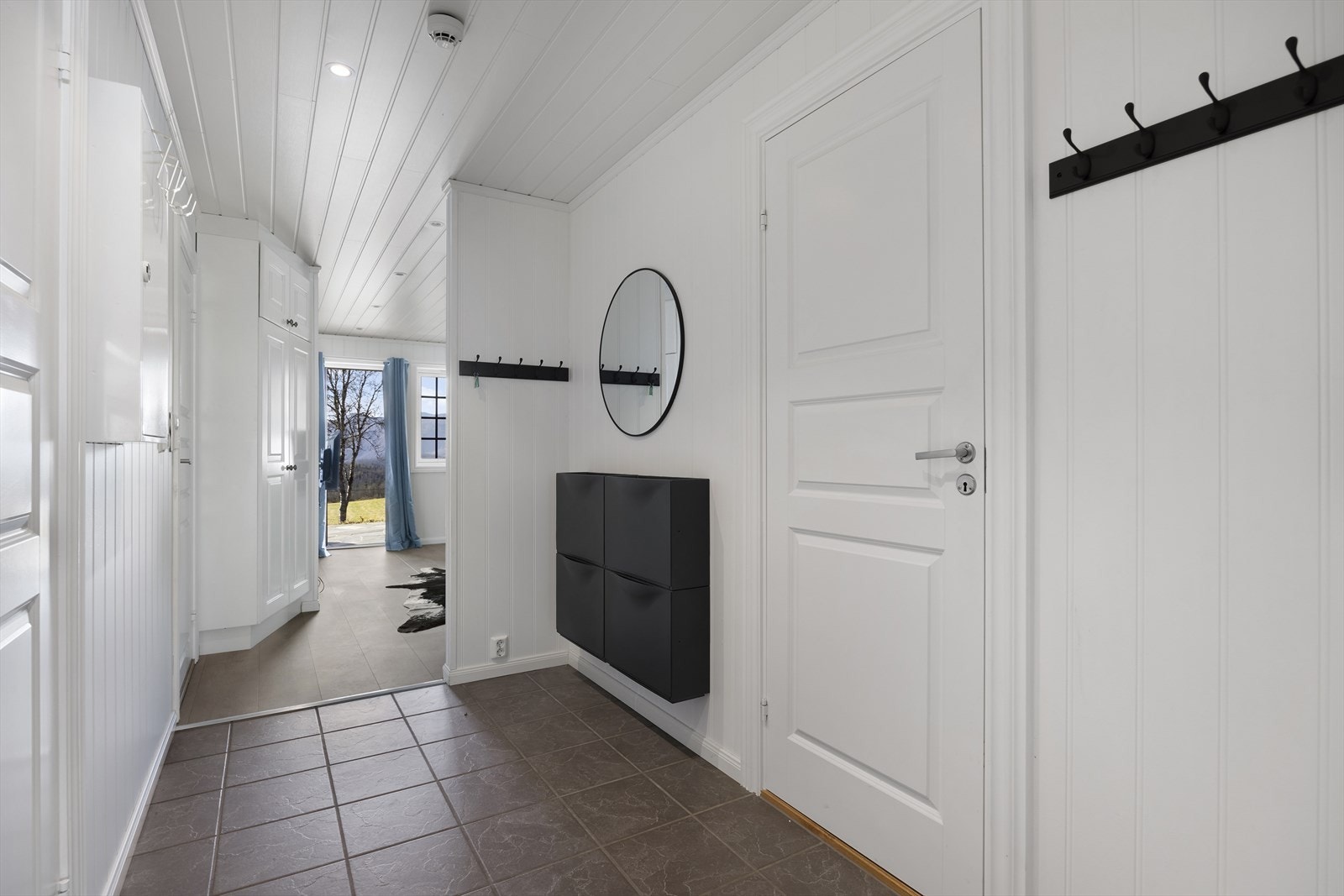 Romslig og innbydende entré med flislagt gulv. Galleribilde