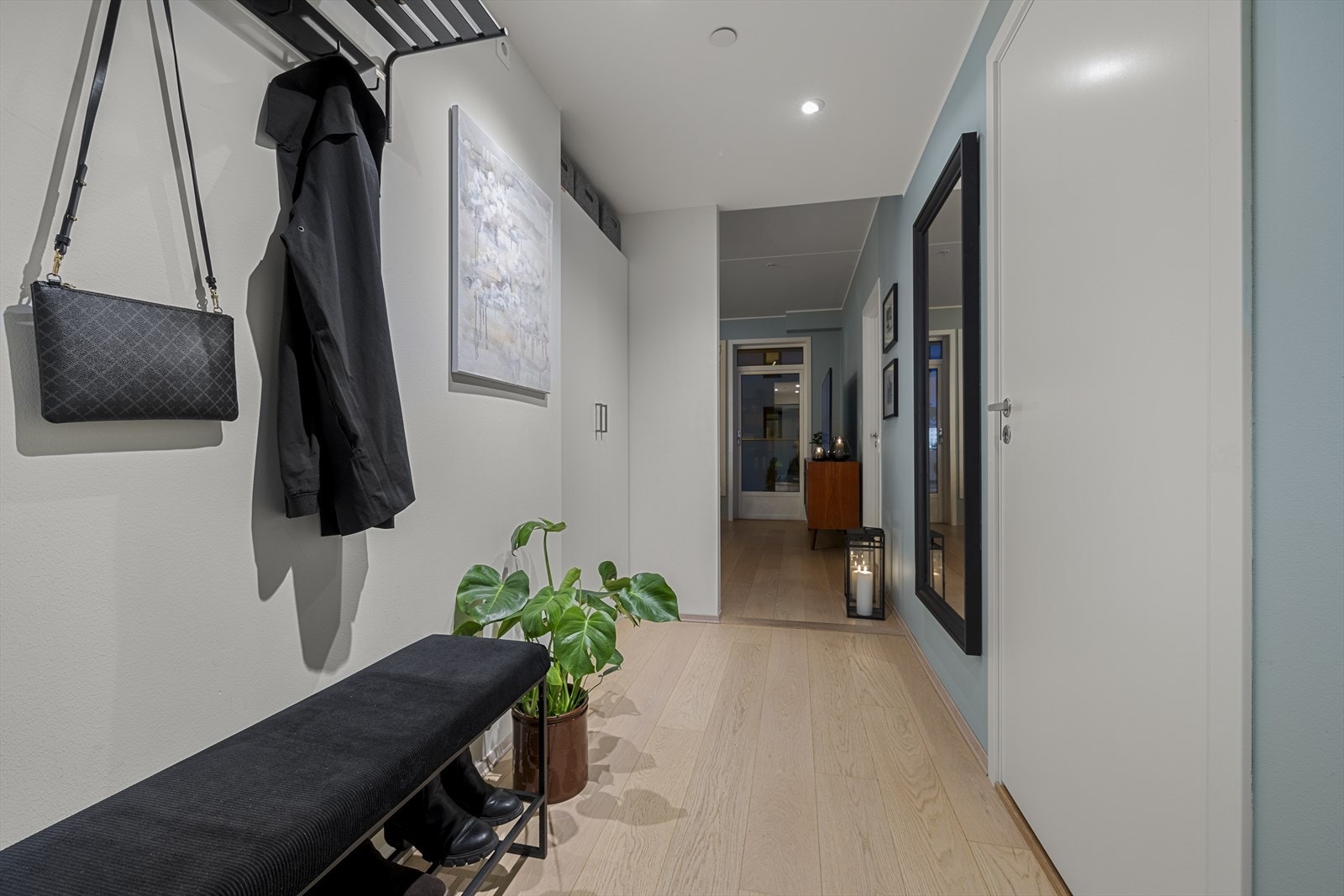 En stilfull entré som gir et flott førsteinntrykk av leiligheten, med parkett på gulvet, lysmalte vegger og downlights i taket for en moderne touch. Galleribilde