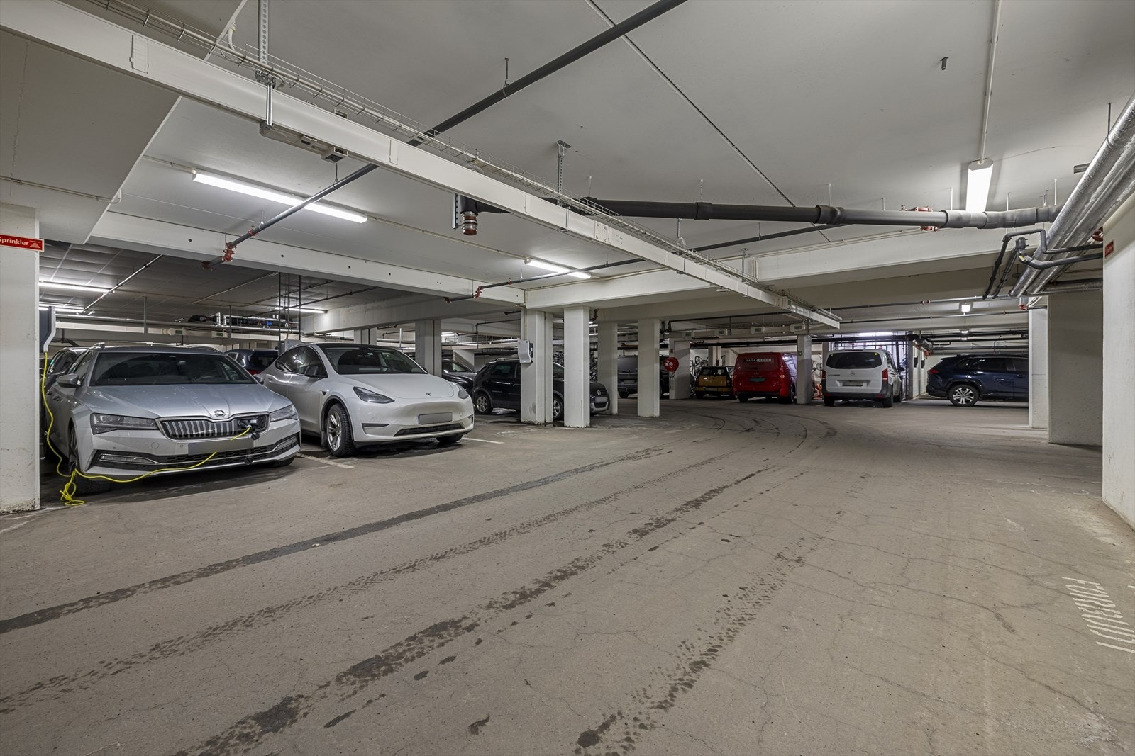 Leiligheten har egen plass i et lukket garasjeanlegg på ca. 12 kvm. Garasjeplassen er praktisk plassert med kort avstand til heis og trapp som leder direkte opp til leiligheten. Det er også installert el-bil lader med kapasitet på opptil 22 kW. Galleribilde