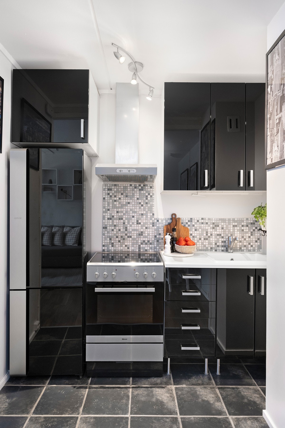 Åpen kjøkkenløsning. Pen kjøkkeninnredning fra 2016 med glatte fronter og fliser over laminert benkeplate. Ventilator med kullfilter over komfyr. Galleribilde