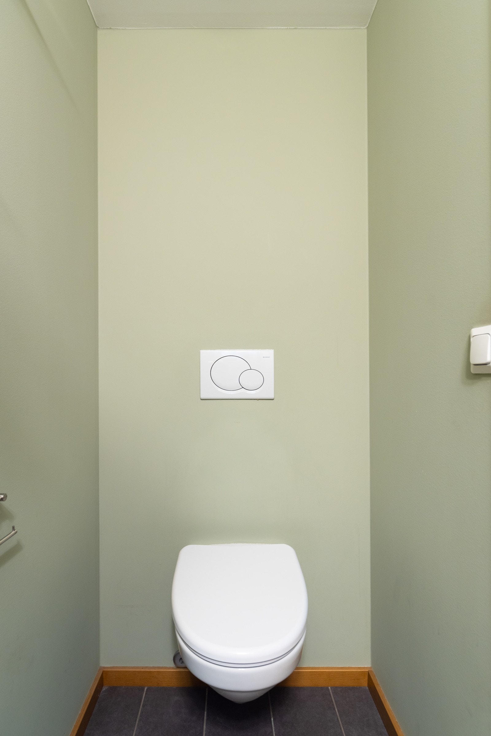 Innredet med vegghengt servant med ett-greps armatur, underskap, speil med belysning over og vegghengt toalett. Galleribilde