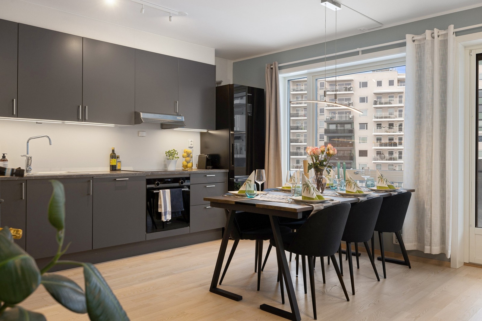 Kjøkkenet er praktisk plassert langs den ene veggen og har en elegant, takhøy innredning. De glatte, mørke frontene og benkeplaten i laminat gir et stilrent og moderne preg Galleribilde