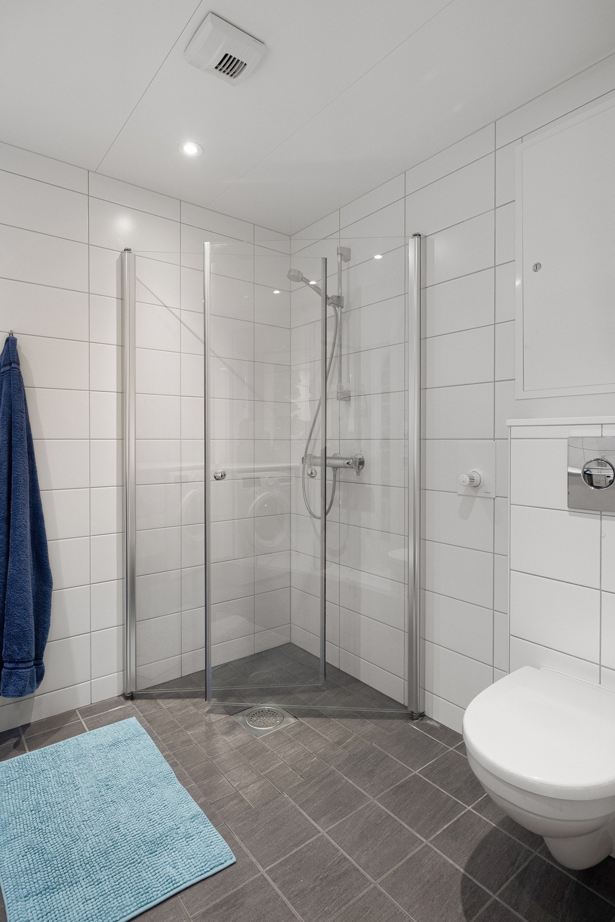 Badet er utstyrt med et vegghengt toalett, nedsenket dusjsone med innfellbare glassdører, samt avtrekk koblet til det balanserte ventilasjonsanlegget. Galleribilde