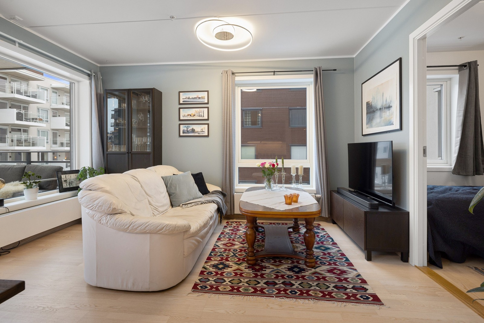 Den lyse stuen har store vinduer som gir en luftig atmosfære, med flere innredningsmuligheter og tilgang til balkongen. Galleribilde