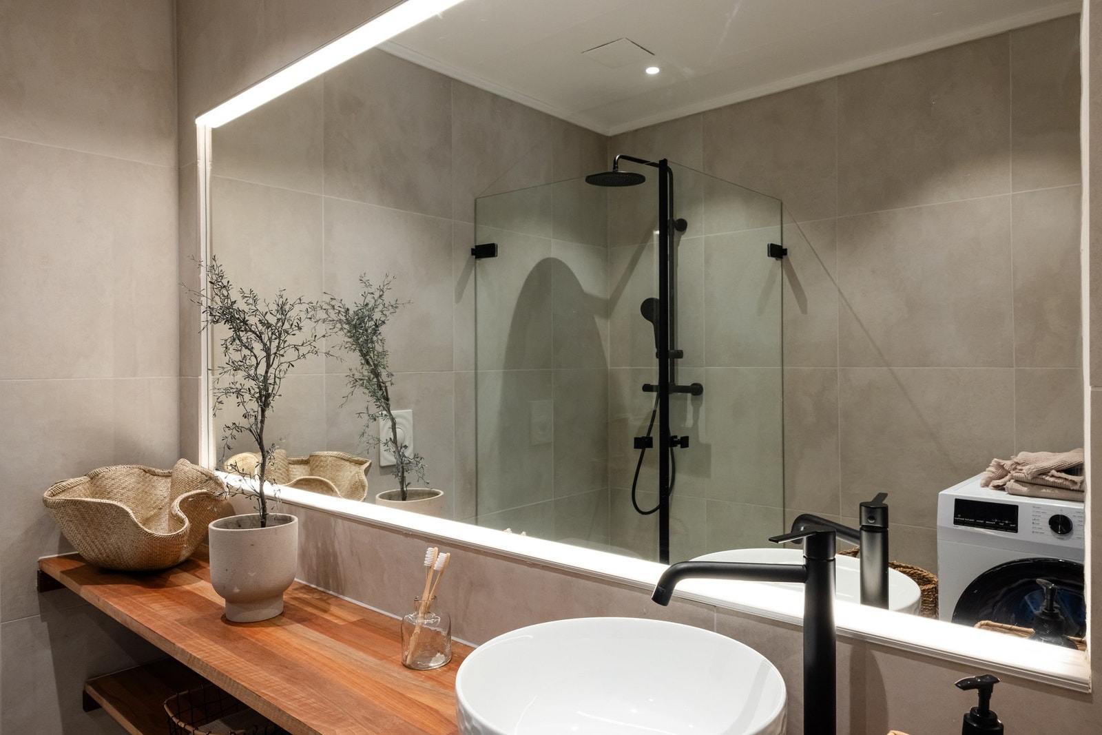 Badet er utstyrt med vegghengt toalett, benkeplate med ovenpåliggende servant, stort speil, samt regnfalldusj og dusjdører. Galleribilde