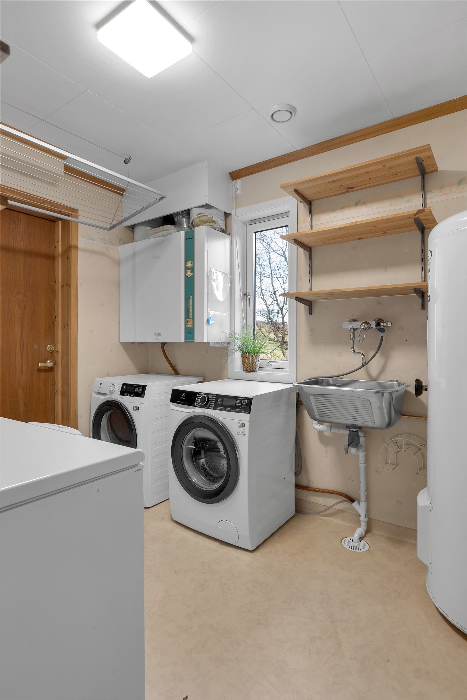 På motsatt side av gangen finner du et stort og praktisk vaskerom med utgang ut til baksiden av boligen Galleribilde