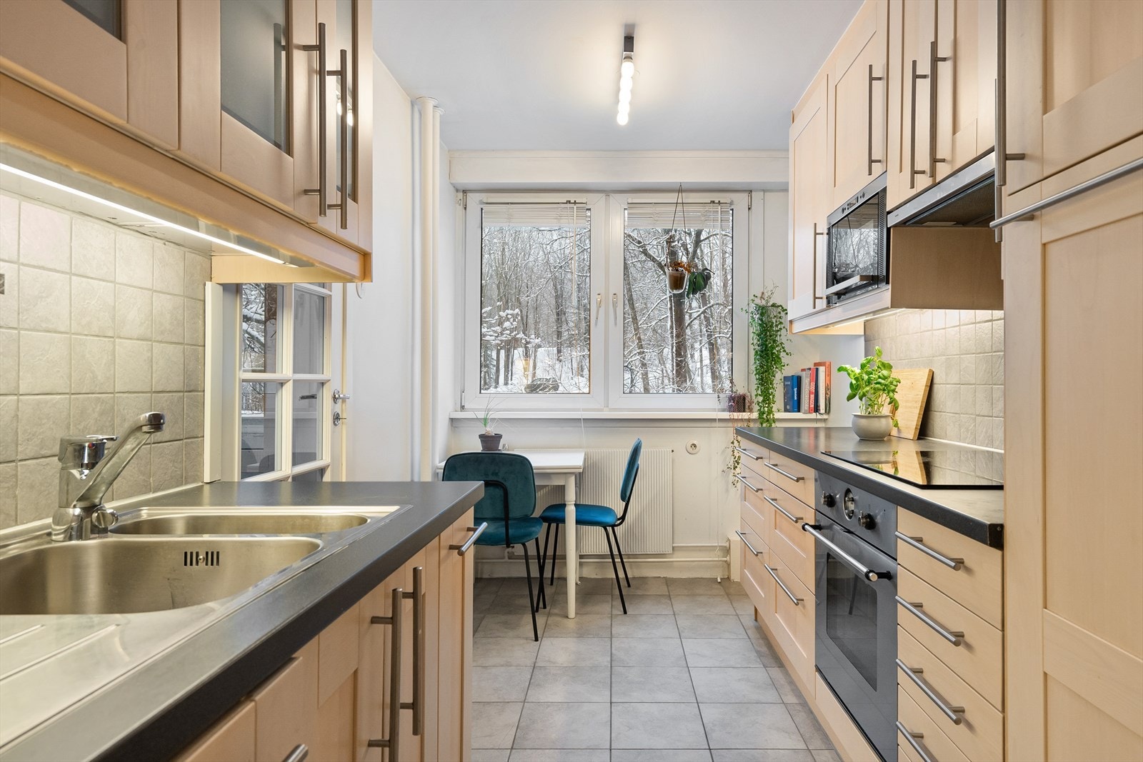 Pen kjøkkeninnredning fra IKEA med fliser mellom overskap og laminert benkeplate. Det er lys/lyslist under overskap. Galleribilde