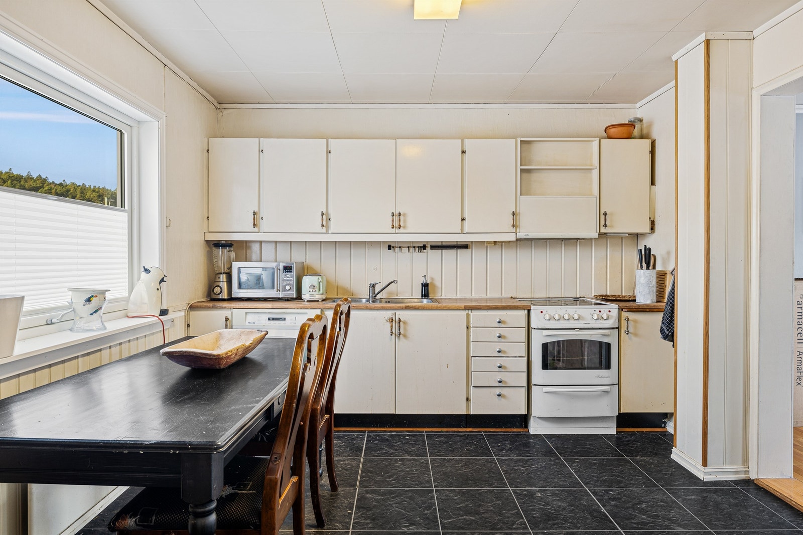 Kjøkken med spiseplass, malt innredning, stålvask og ventilator. Galleribilde