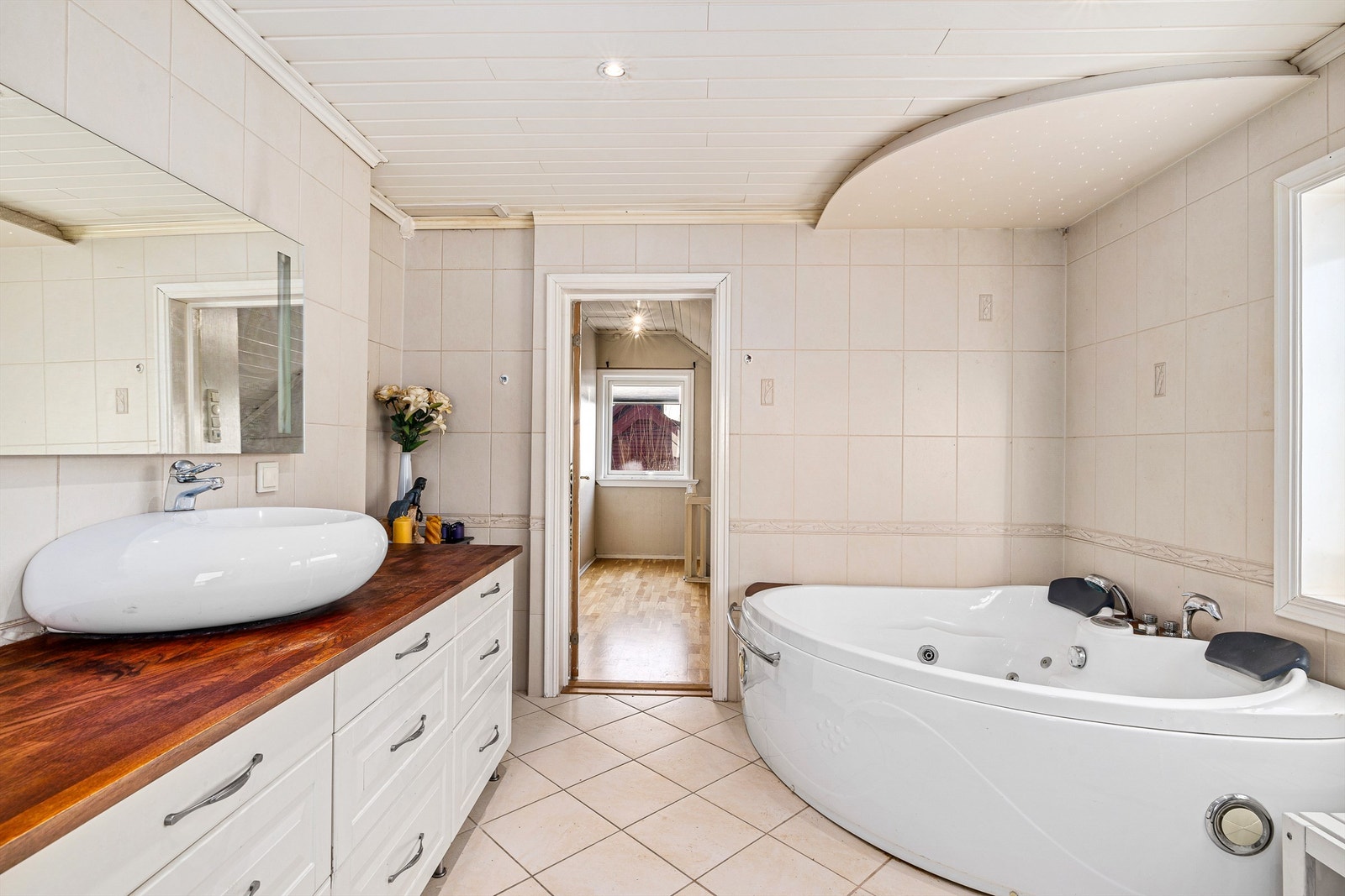 Stort bad med hjørneboblekar, dusjkabinett, design wc og servant med skap under. Galleribilde