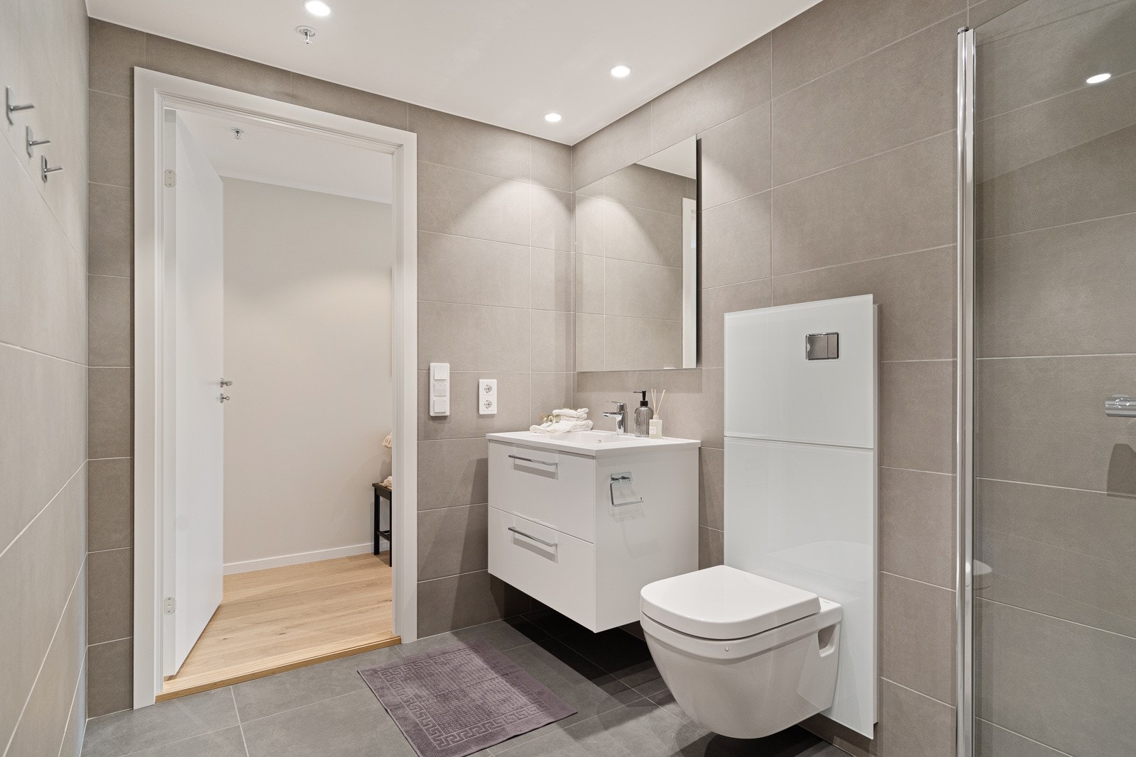 Badet har lekre fargekombinasjoner på flisene og spotter i tak Galleribilde