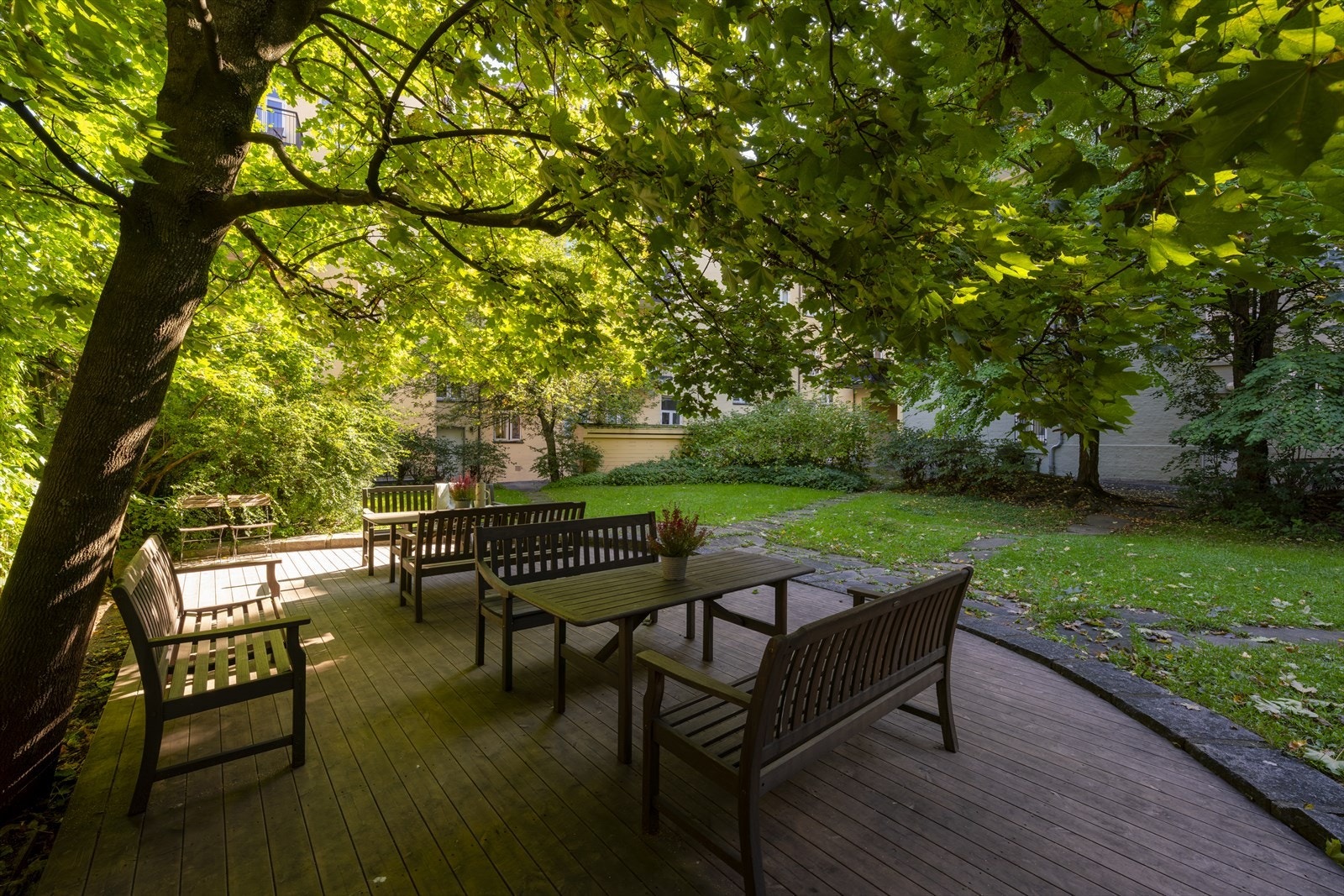 Hagen i bakgården er pent opparbeidet med platting, sittegrupper, plen, busker og trær. Galleribilde