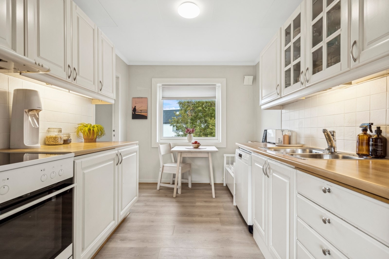 Kjøkkenet er praktisk etablert i eget rom og har en tidløs hvit innredning. Galleribilde