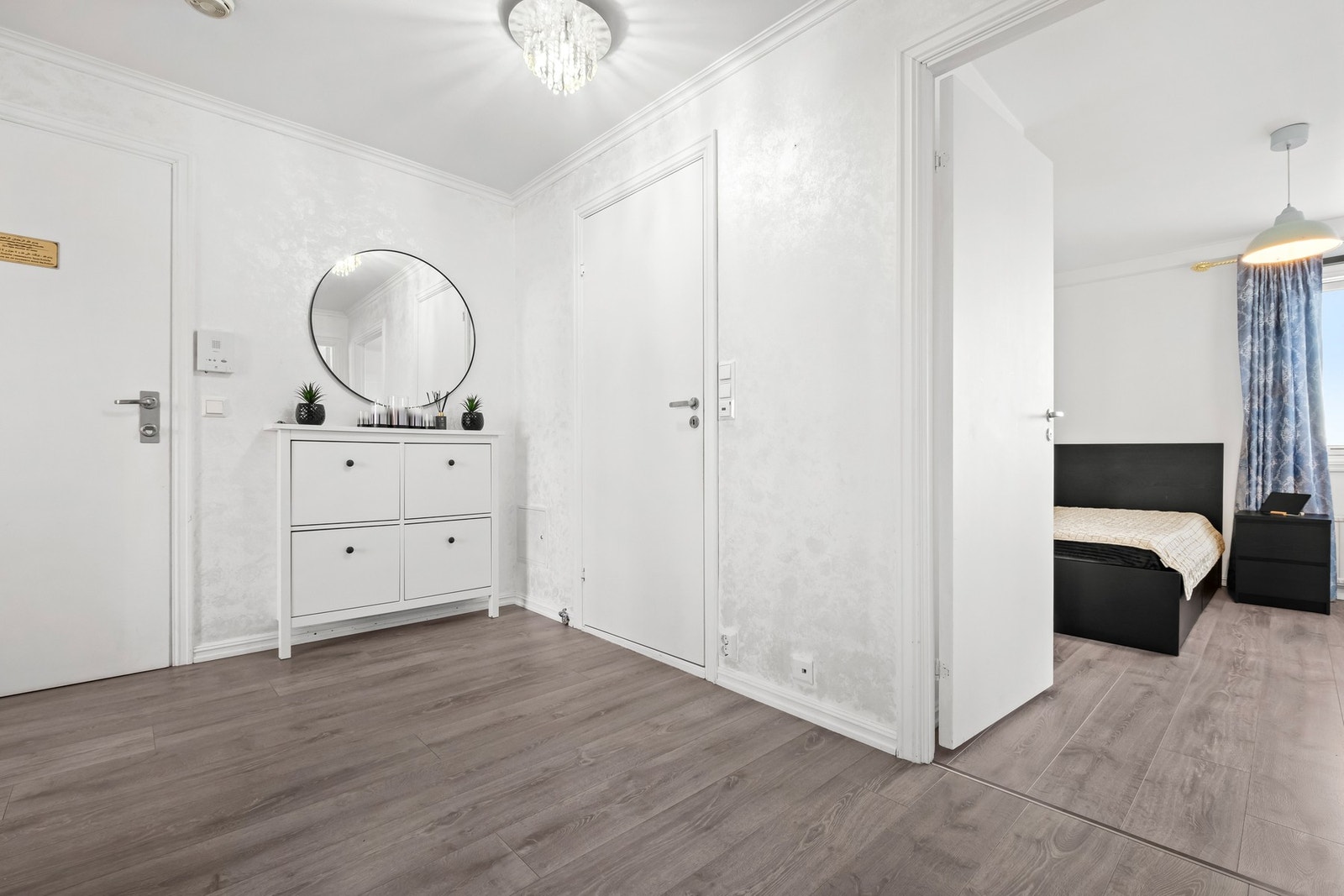Boligens entré er romslig og lys med nyere laminatgulv og pen tapetsert vegg Galleribilde