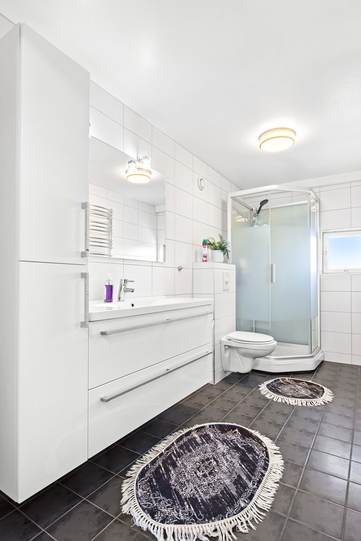 Badet har pent flisvalg, vegghengt wc og dusjkabinett. Det er også håndkletørker på vegg som er meget praktisk! Galleribilde