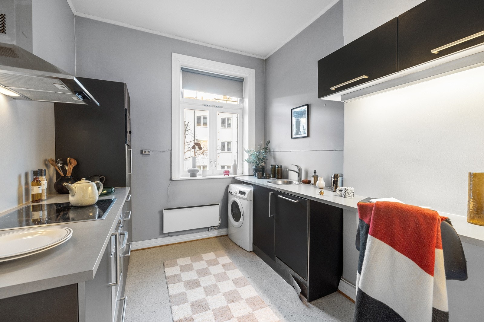 Leiligheten har et innholdsrikt kjøkken med slette og mørklaminert fronter og 28mm grålaminert benkeplate av spon med nedfelt rund vaskekum i børstet stål og ettgreps blandebatteri i rustfritt stål fra Hans Grohe. Galleribilde