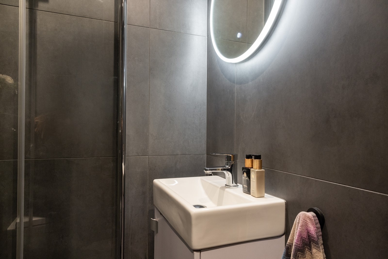 - Baderommet er innredet med vegghengt toalett med innebygget sisterne og synlig avrenningsspalte, servantinnredning med laminert front, heldekkende porselenservant, ett-greps servantarmatur og rundt speil med led bakbelysning - Galleribilde