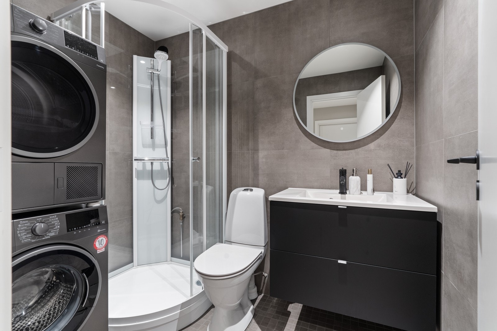 Lekkert flislagt bad med dusjkabinett, moderne innredning, vaskasøyle og gulvvarme. Galleribilde