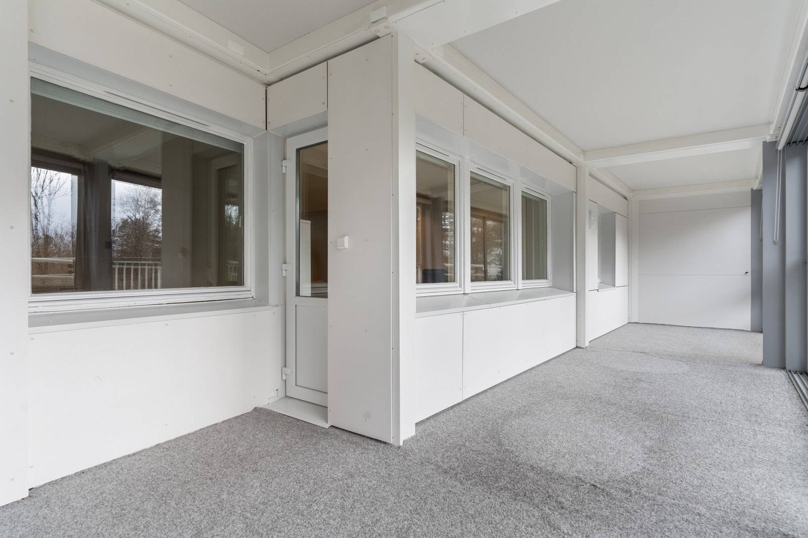 Stor innglasset veranda med teppelagt gulv. Et romslig arealtilskudd til boligen på sommeren. Galleribilde