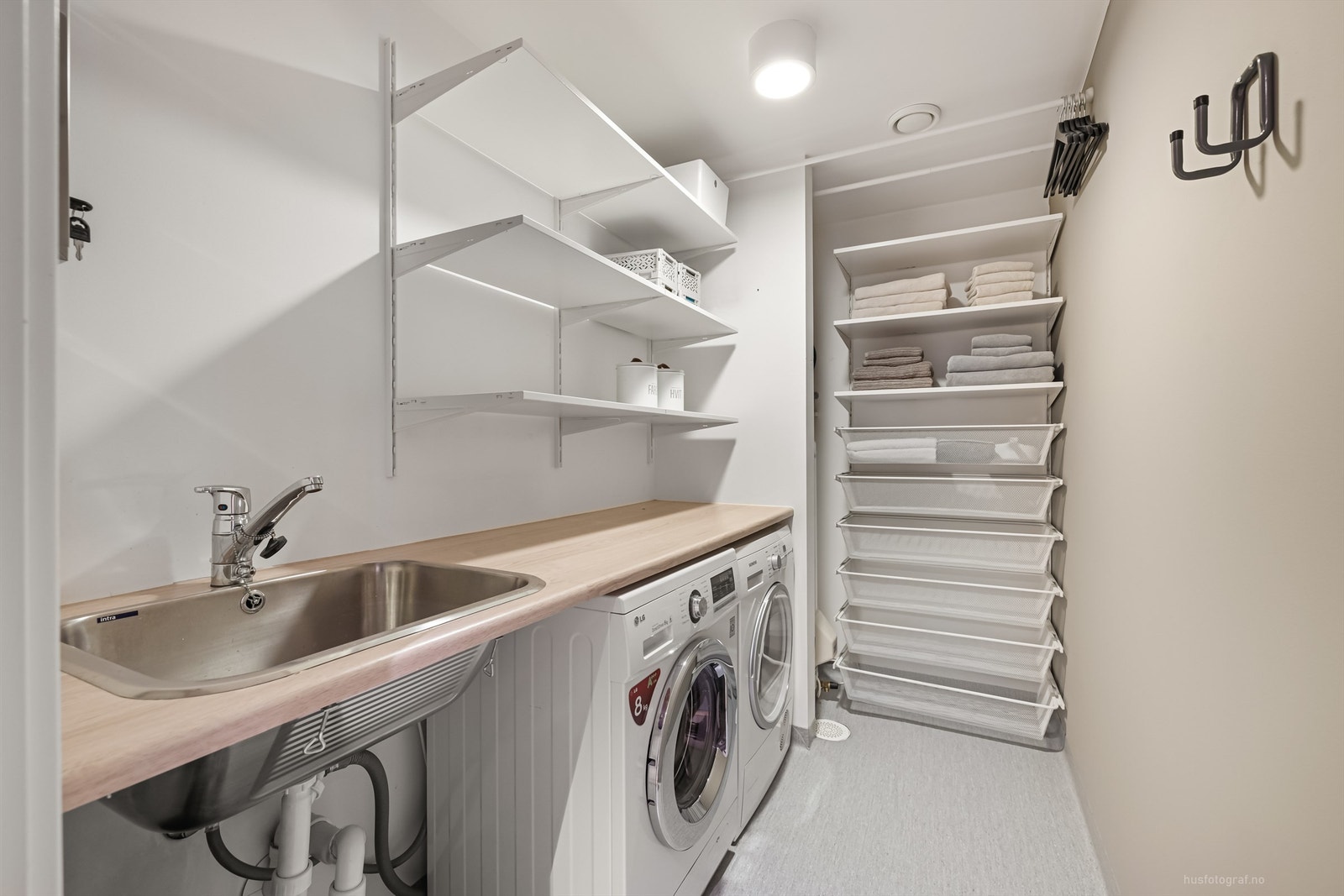 Praktisk vaskerom med utslagsvask, vegghengte hyller og skuffinnredning Galleribilde