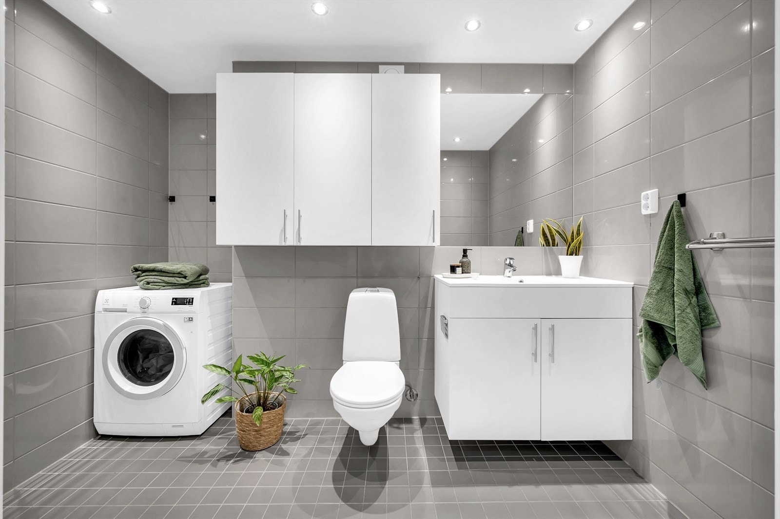 Rommet består av vegghengt toalett, dusjhjørne med svingbare glassdører og baderomsinnredning med servant nedfelt i innredning. Det er opplegg for vaskemaskin. Galleribilde