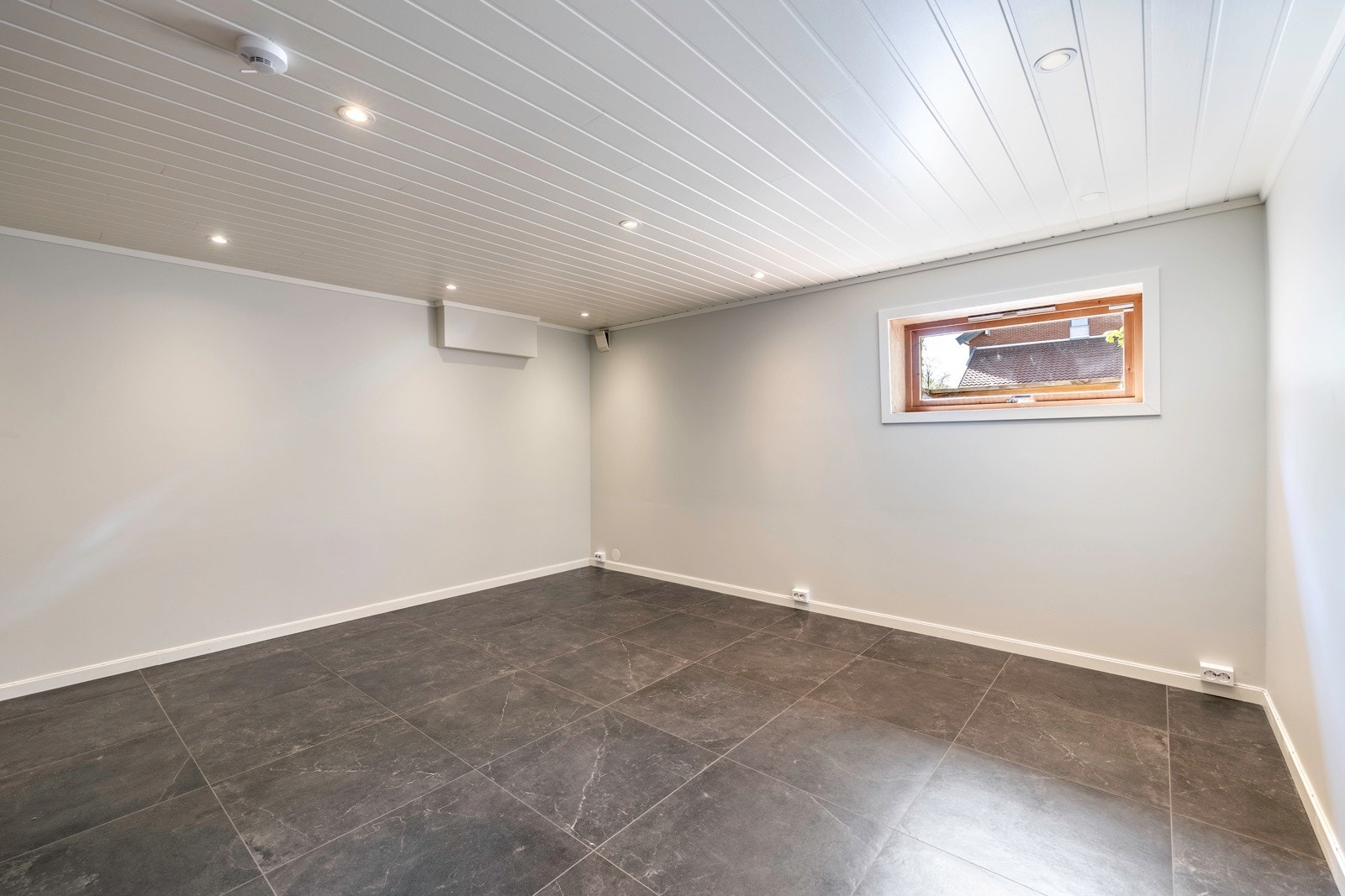 I kjelleretasjen har boligen et innredet rom benyttet som kjellerstue, pusset opp i 2024. Stuen gir et flott inntrykk med mørkt gulv, lyse vegger og downlights i himlingen. Galleribilde