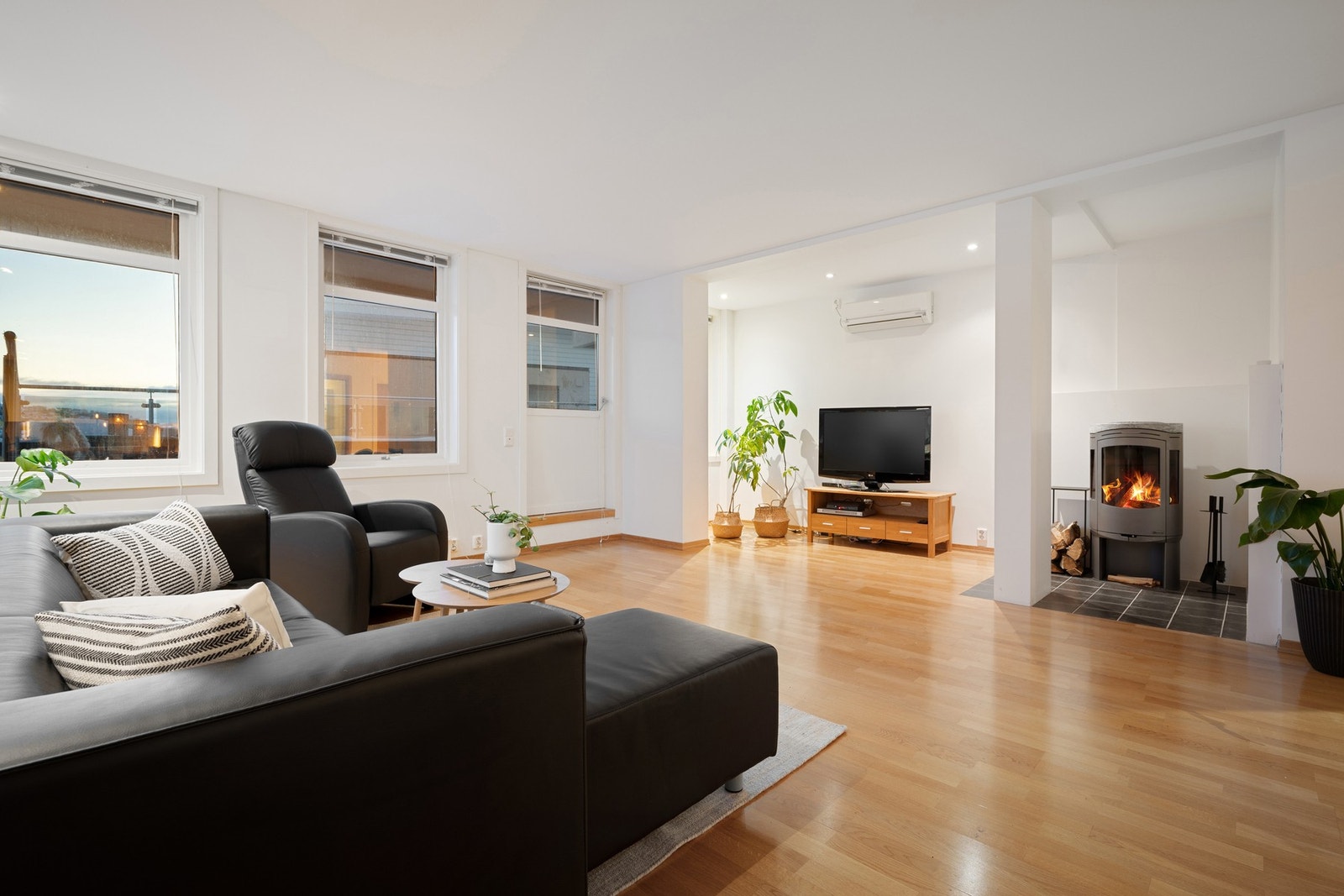 Hyggelig stue med stilrene overflater, samt veggmontert varmepumpe som gir deg behagelig innetemperatur sommer som vinter Galleribilde