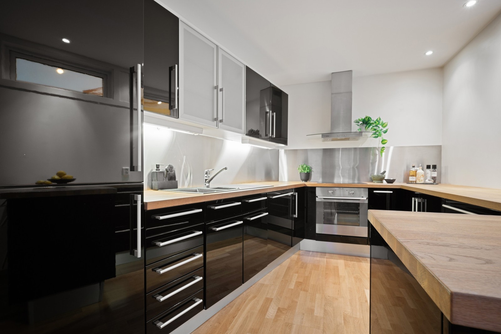 Innredning med glatte fronter og stålplate mellom kjøkkenbenk og overskap Galleribilde