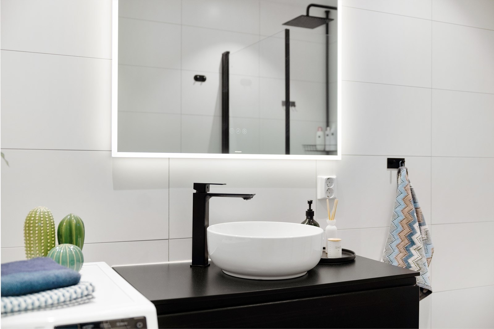 Badet er innredet med servantskap og topp servant, speil med innebygd belysning, vegghengt klosett med innebygd sisterne, samt en stilren dusjsone med innfelte dusjdører i herdet glass. Galleribilde