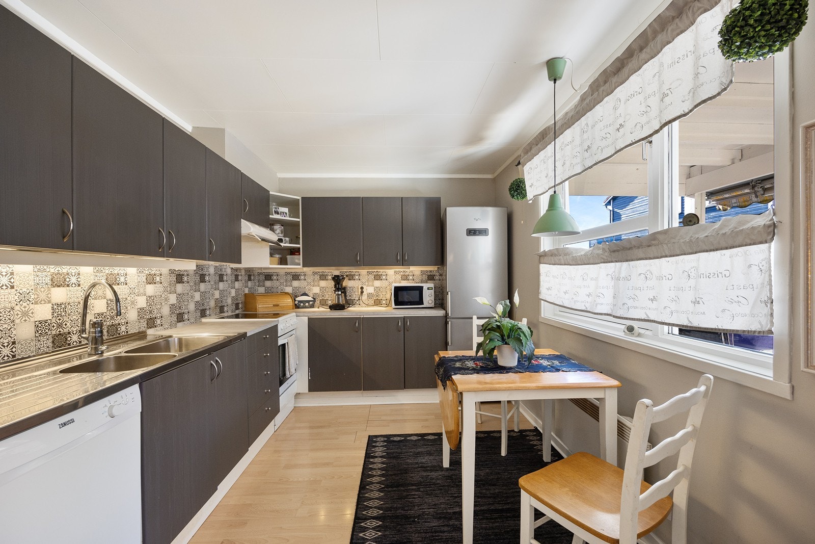 Kjøkkeninnredningen har mørke, glatte fronter og laminert benkeplate. Galleribilde