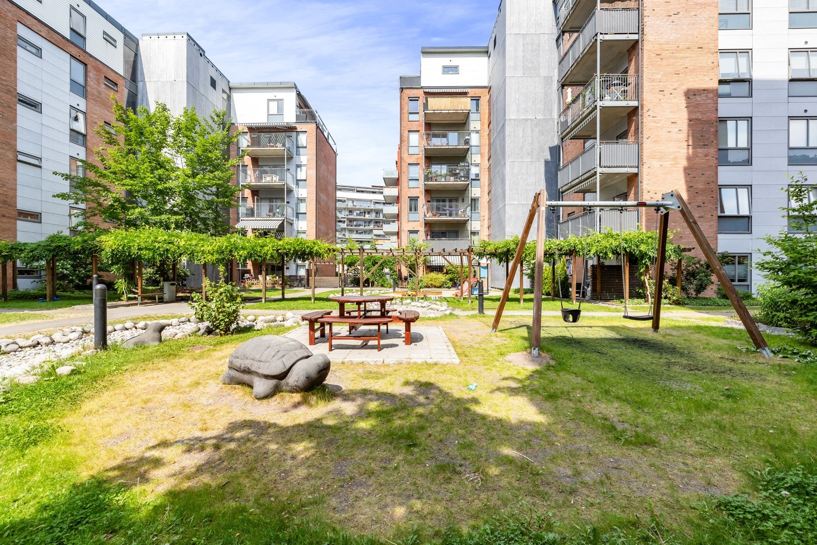 Beboerne disponerer store grøntarealer med grønne plener og lekeplasser Galleribilde