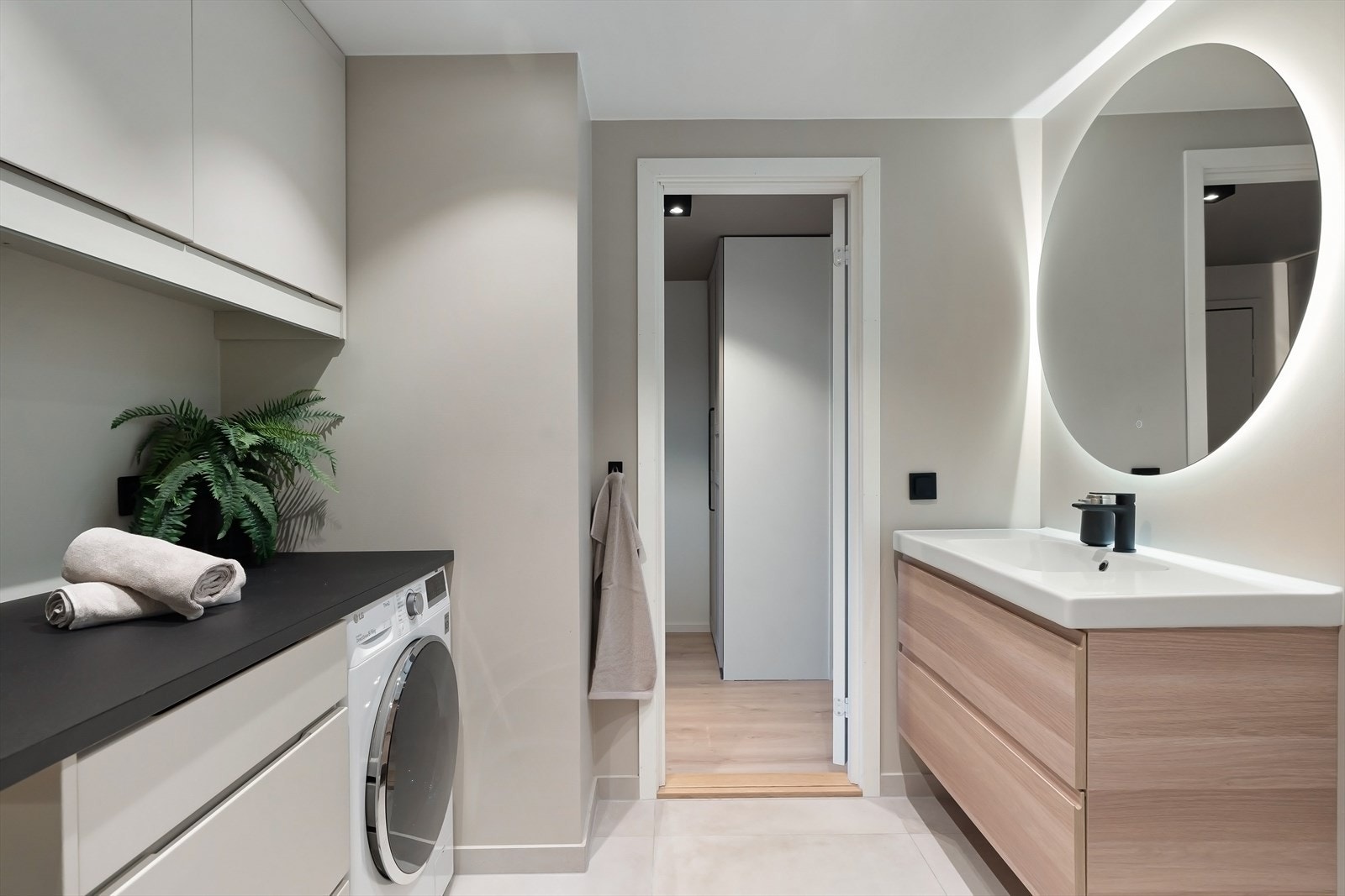 Baderomsinnredning bestående av benkeskap med glatte fronter. Nisje til vaskemaskin. Galleribilde