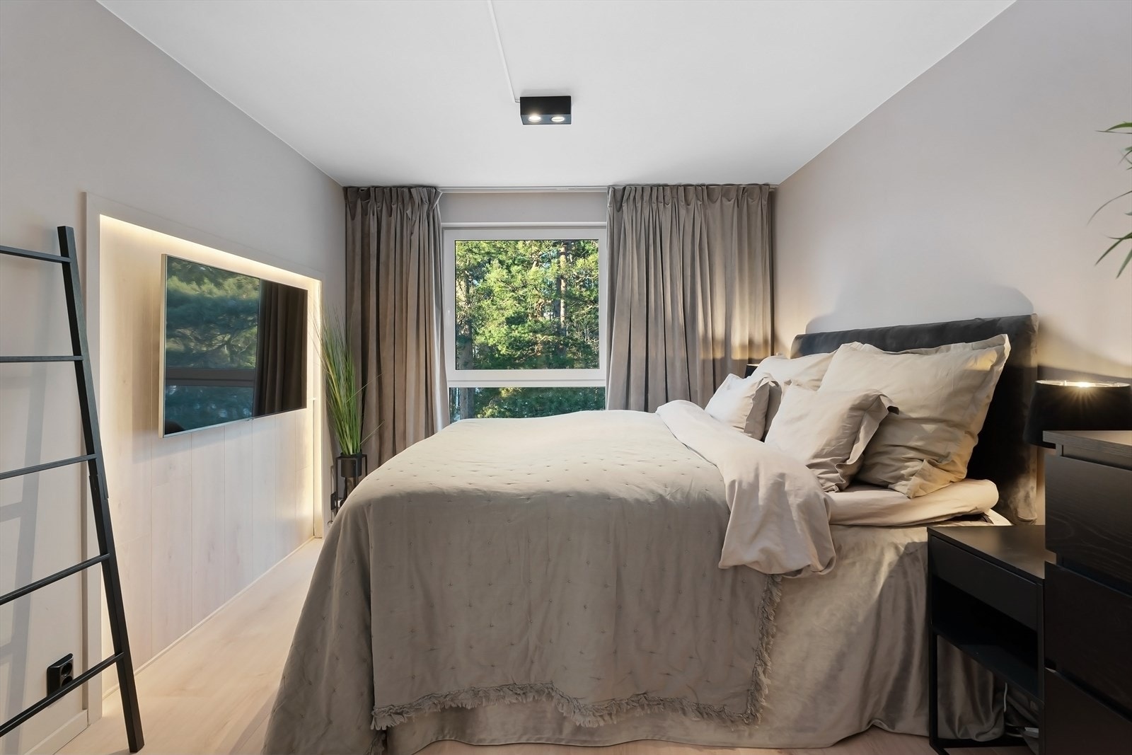 Romslig hovedsoverom med frodig utsyn. Praktisk og stilfull nisje med belysning som omramming for TV. Galleribilde