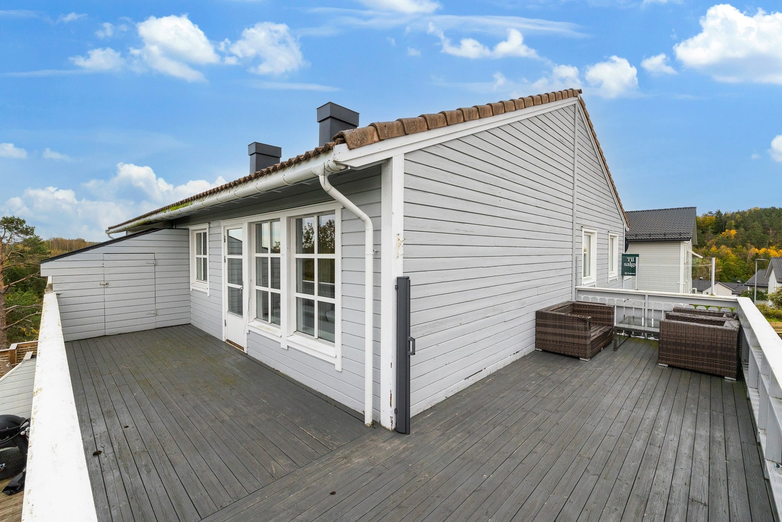 Stor terrasse som bader i sol strekker seg rundt deler av leiligheten Galleribilde