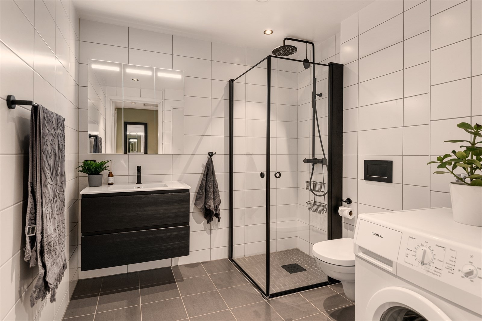 Helfliset bad med varmekabler i gulv. Badet er utstyrt med servant med innredning, dusj, og vegghengt toalett. Det er opplegg til vaskemaskin og tørketrommel. Galleribilde