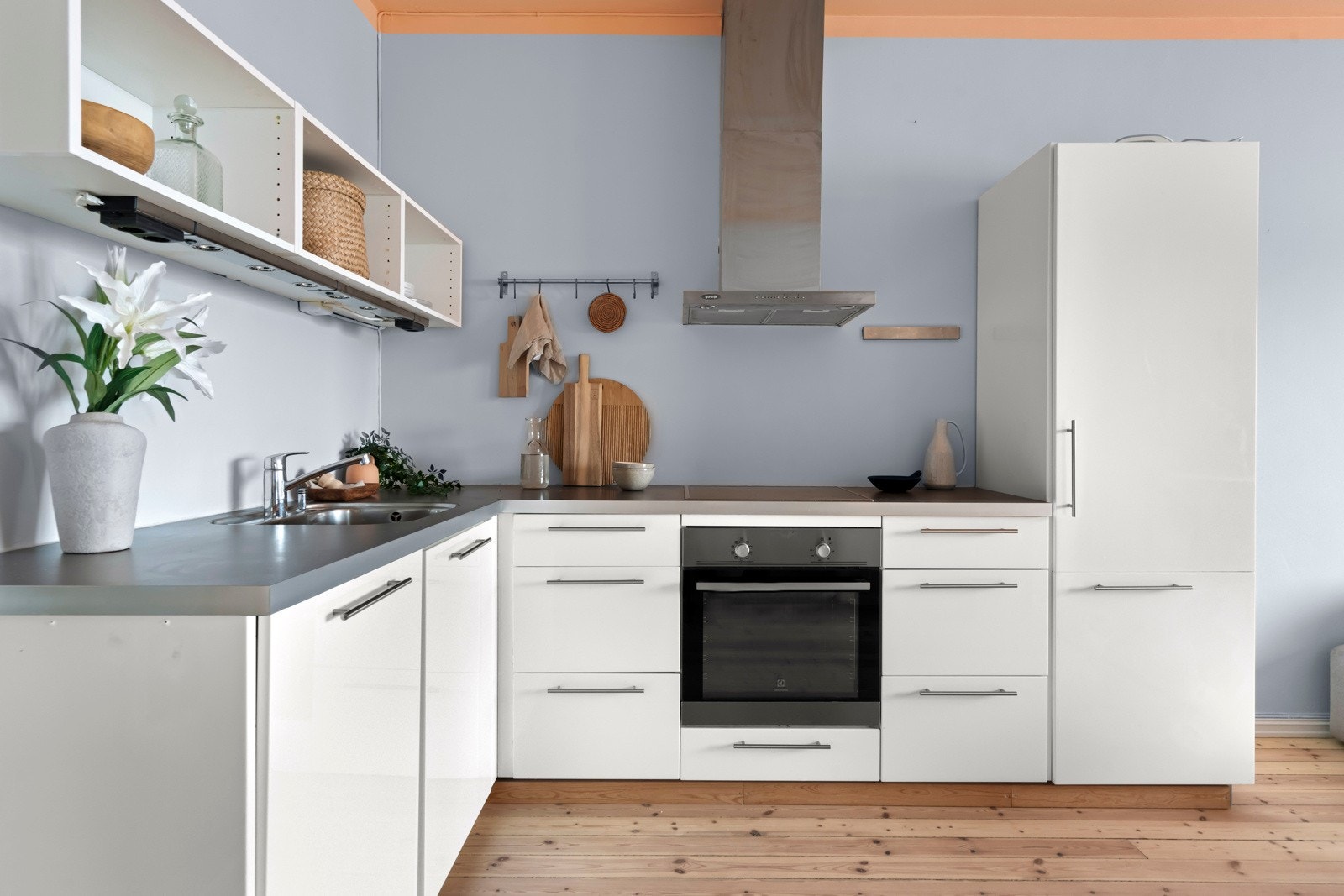 Pent tidløst kjøkken i lys utførelse. Integrerte hvitevarer gir et strømlinjeformet og stilrent uttrykk. Slitesterk benkeplate i laminat. Avtrekksvifte med kullfilter i børstet stål over kokesonen og utslagvask med ettgreps blandebatteri. Galleribilde