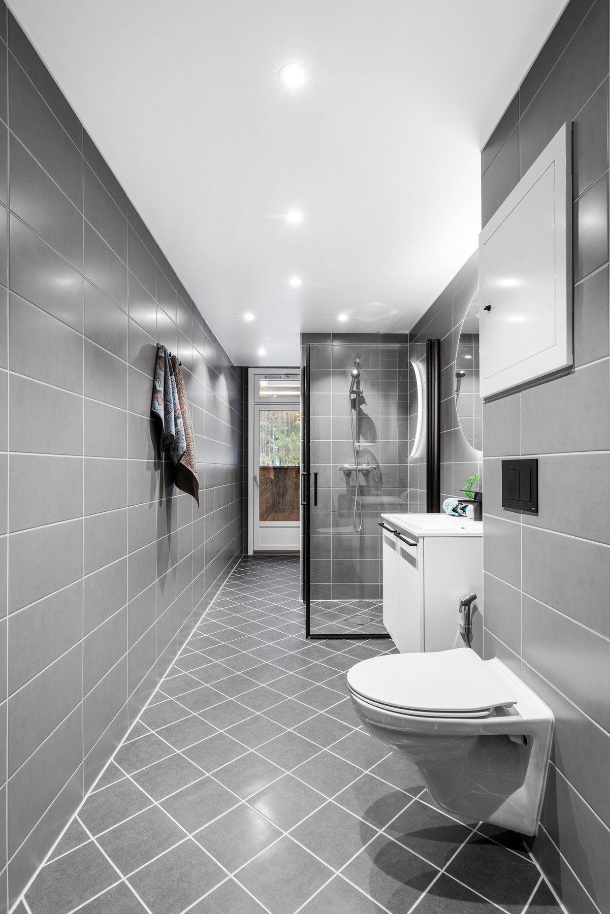 Her er alt nytt med gulvvarme, downlights i himling, vegghengt wc + bidé, stort dusjhjørne med sorte rammer, rundt speil på vegg Galleribilde