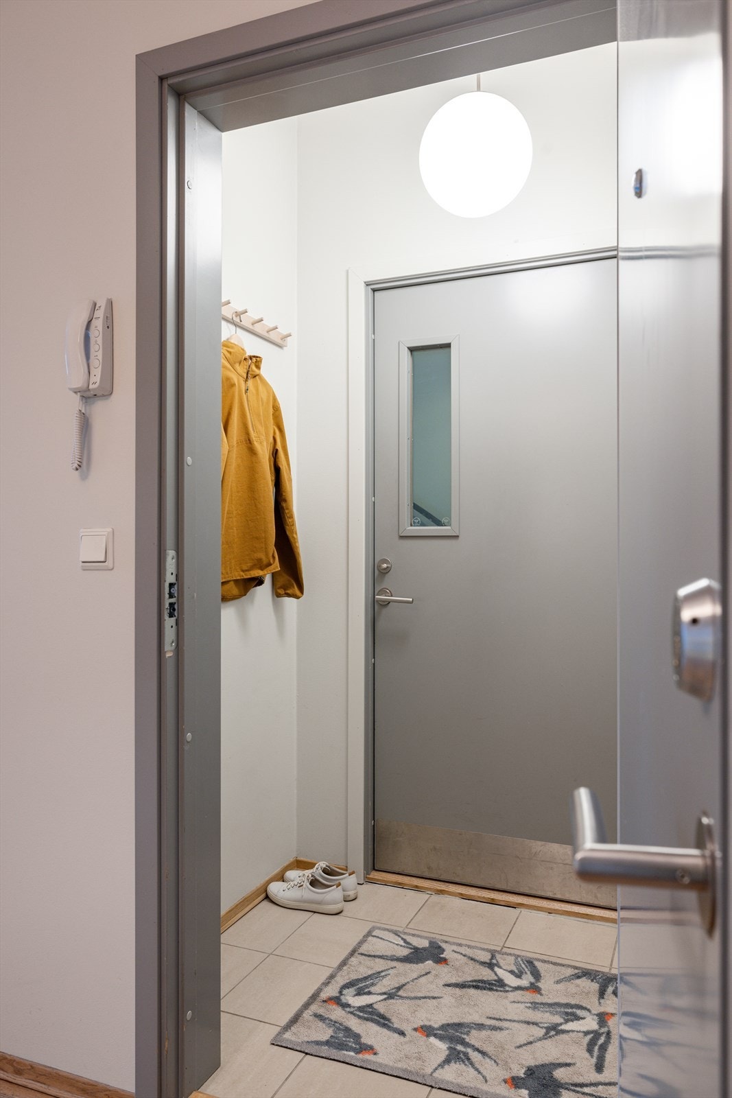 Inntil leiligheten er det to dører og en praktisk entré med flislagt gulv og plass til yttertøy. Galleribilde