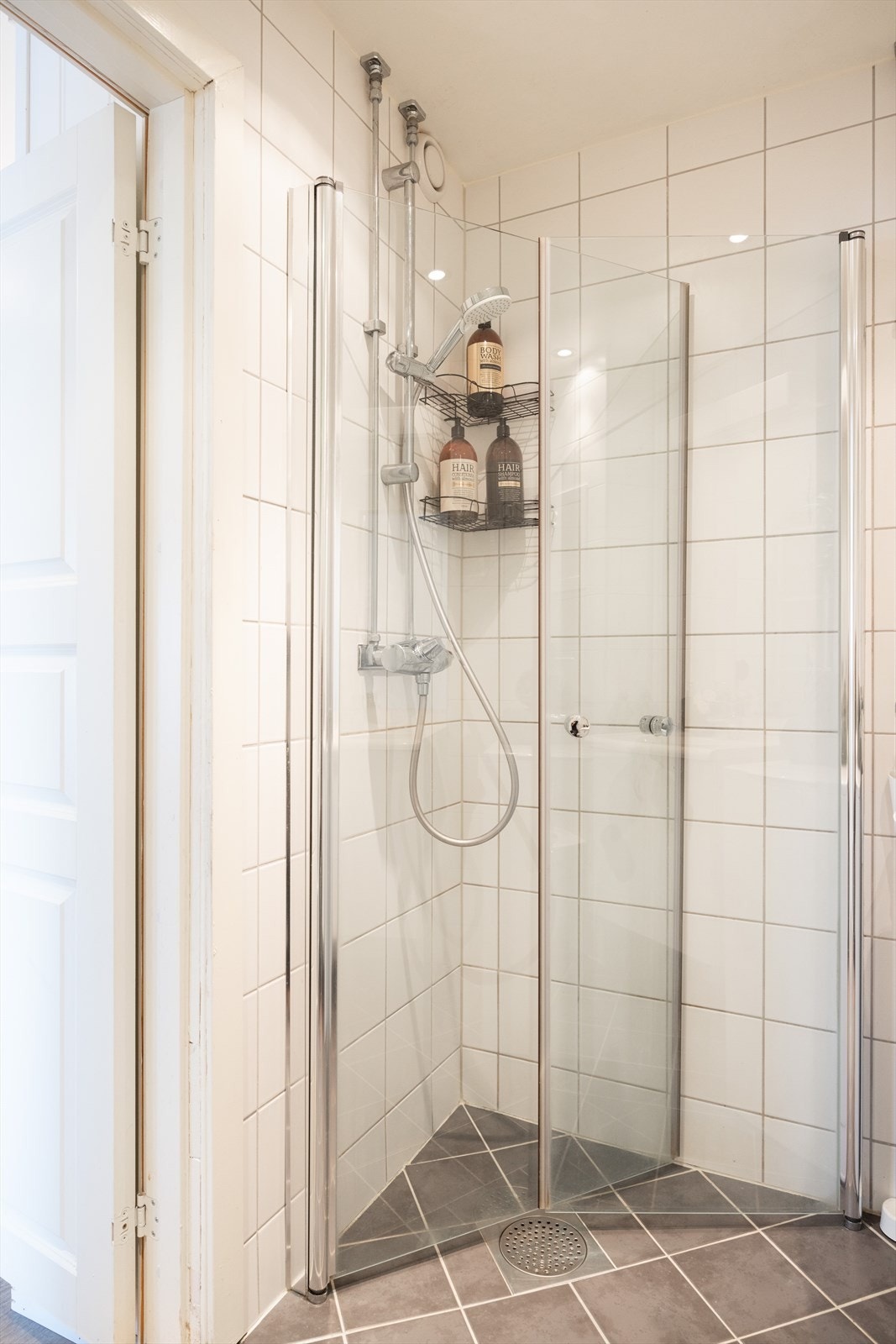 Badet er innredet med vegghengt toalett, servant med innredning og dusjhjørne med svingbare glassdører. Videre er det opplegg for vaskemaskin. Galleribilde