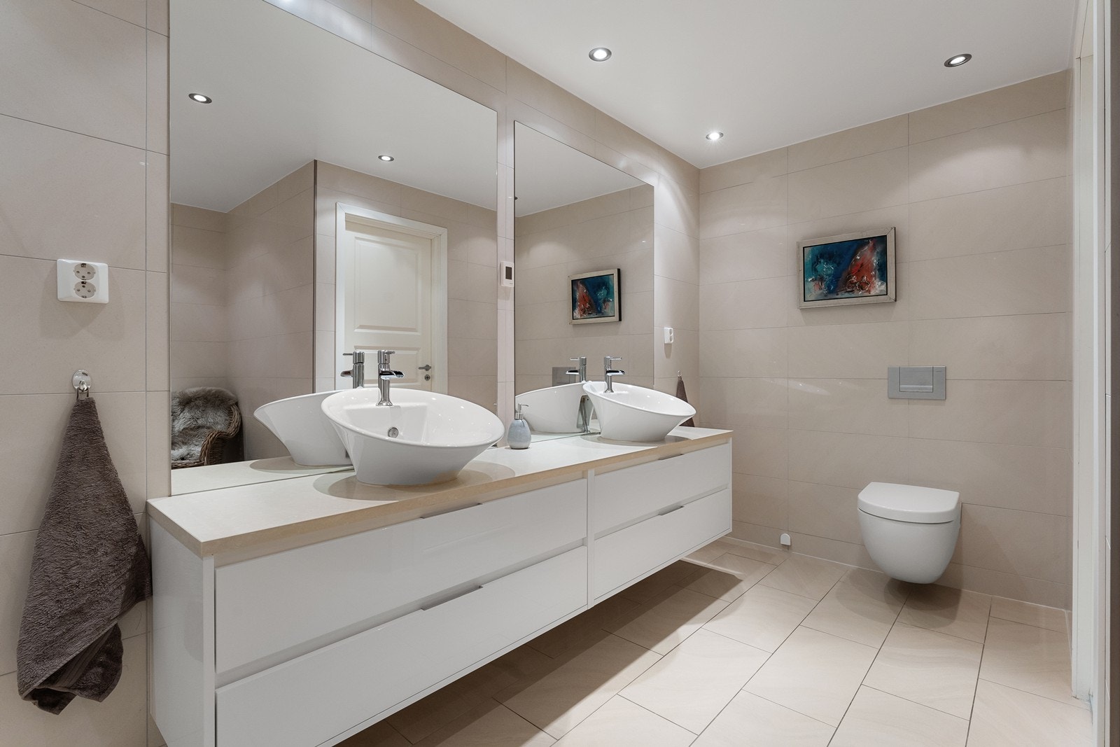 Badet er utstyrt med moderne baderomsinnredning, to store speil over dobbel servant og vegghengt toalett. Galleribilde
