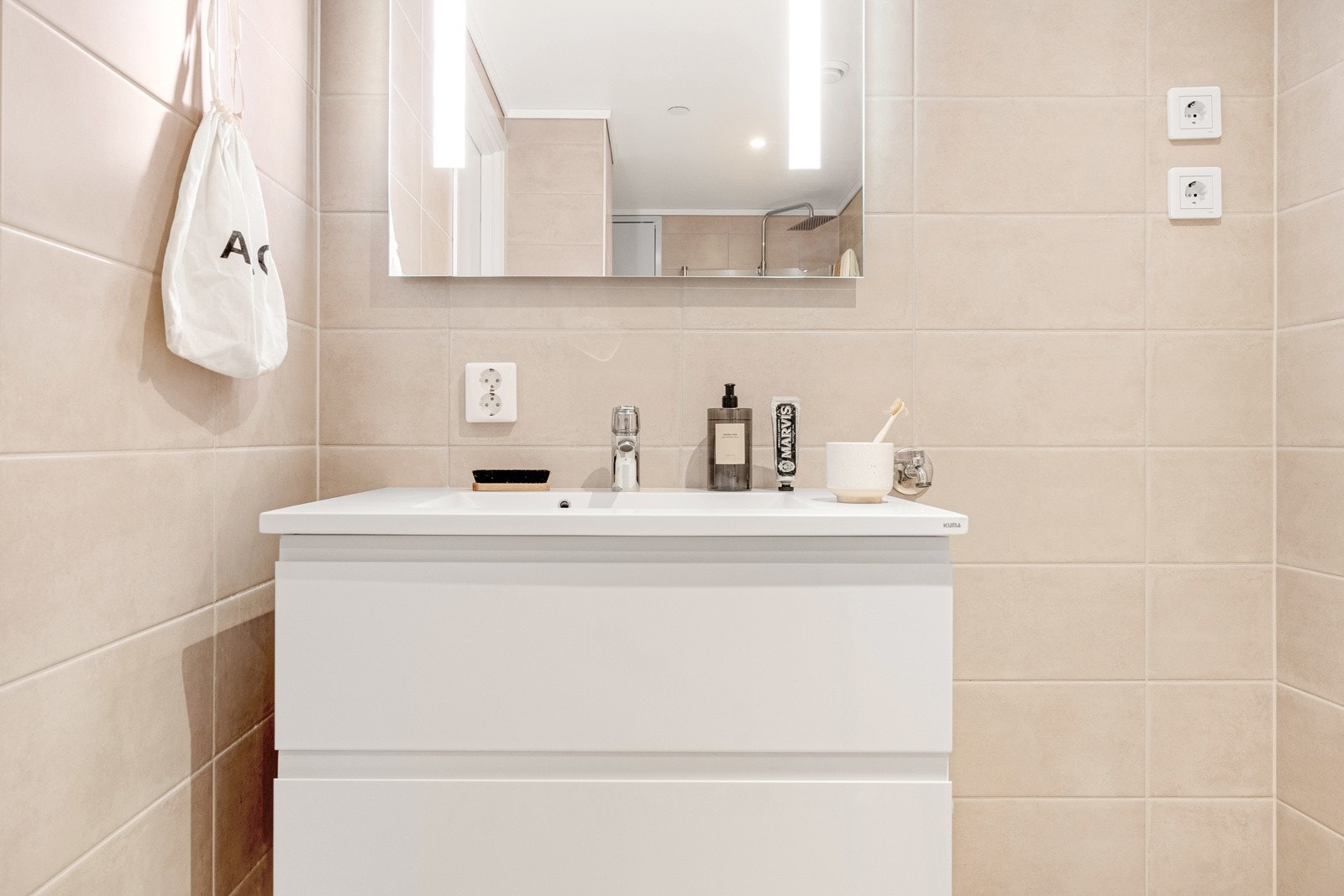 Rommet måler 6 kvm og inneholder stilrent servantmøbel med romslige skuffer, dusj, vegghengt toalett og speil med integrert belysning. Galleribilde