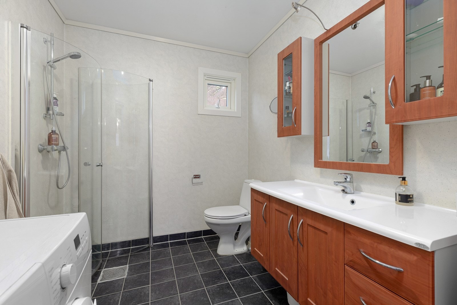 Badet har sveiset våtromsbelegg på vegger og himling, samt fliser med varmekabler på golv. Badet er utstyrt med dusj, wc og innreiing med servant. Galleribilde