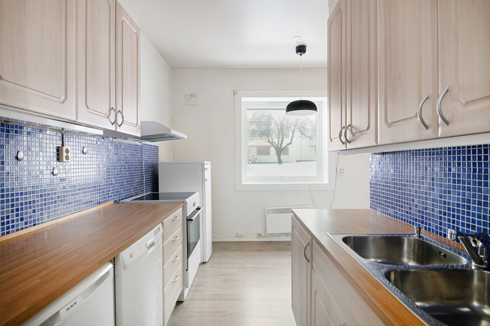 Velholdt kjøkken med folierte profilerte fronter, laminat benkeplate, oppvaskkum, mosaikkfliser på vegg over kjøkkenbenk samt lys under overskap. Opplegg til oppvaskmaskin. Galleribilde