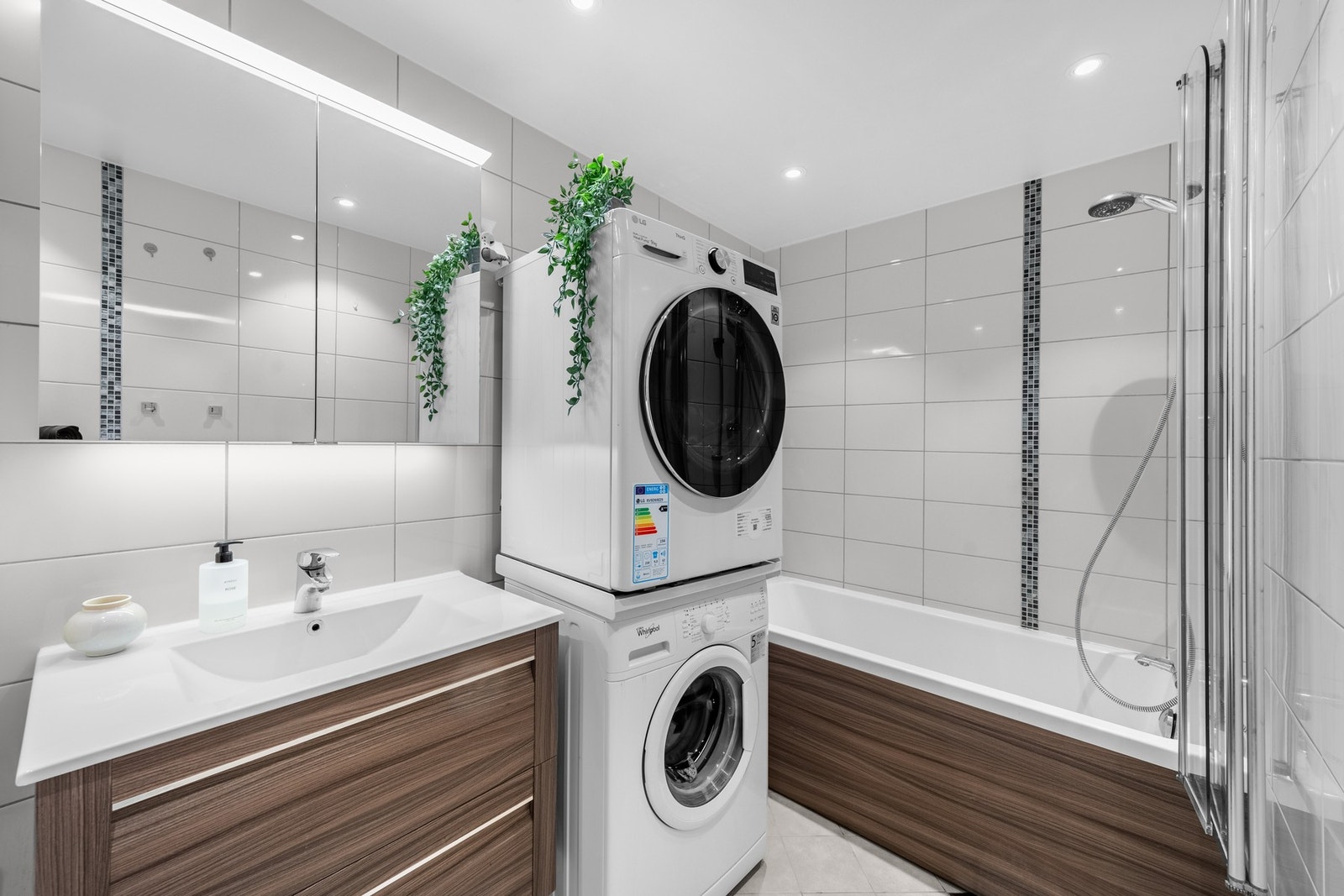 Moderne bad fra 2015! Badet har en stilren og praktisk løsning med lyse fliser på veggene og brune detaljer på innredningen som gir en varm og innbydende atmosfære. Galleribilde