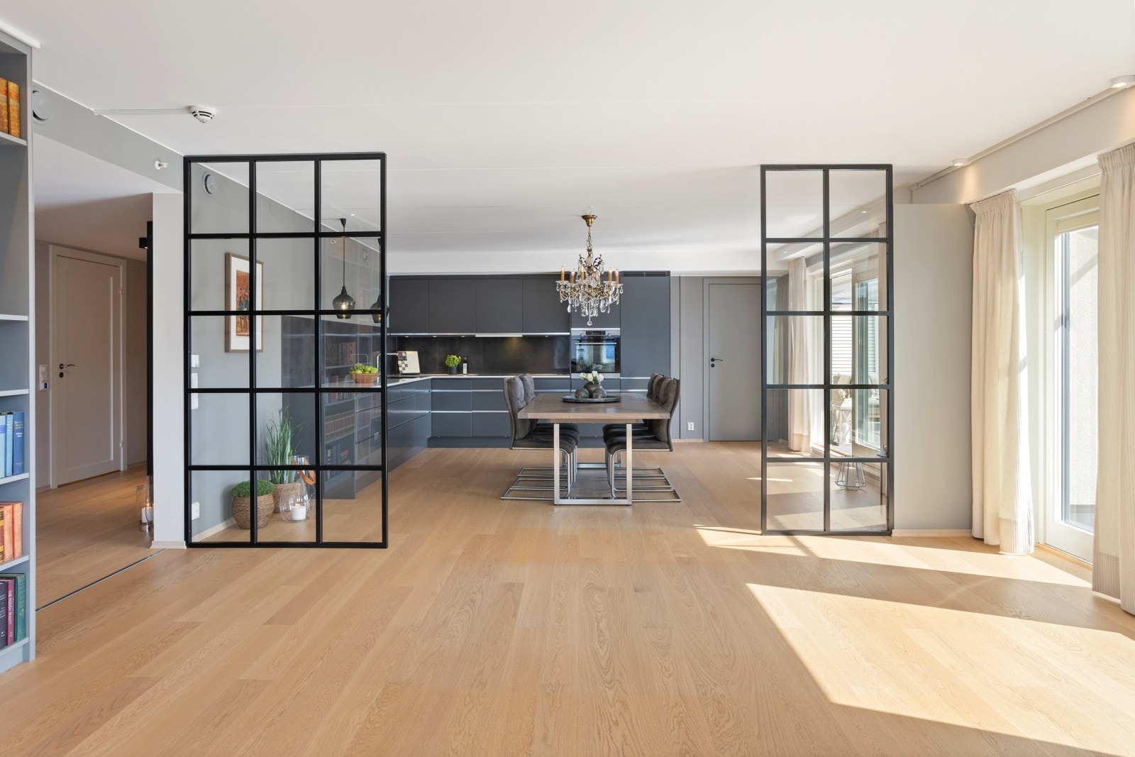 Rommet er lysst og åpent med en transparent vegg mellom kjøkken og stue. Galleribilde