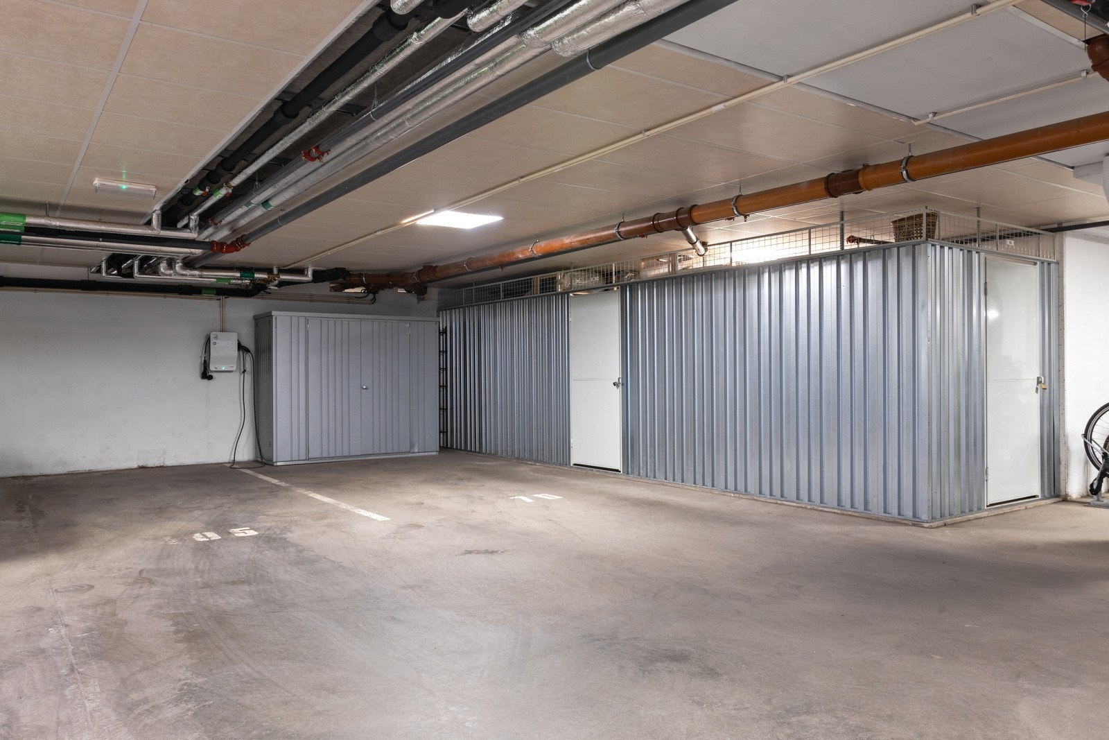 Leiligheten har to parkeringsplasser ved siden av hverandre i garasjeanlegget. Boden til høyre medfølger og det samme gjør den løse boden innerst på plass 1. Galleribilde