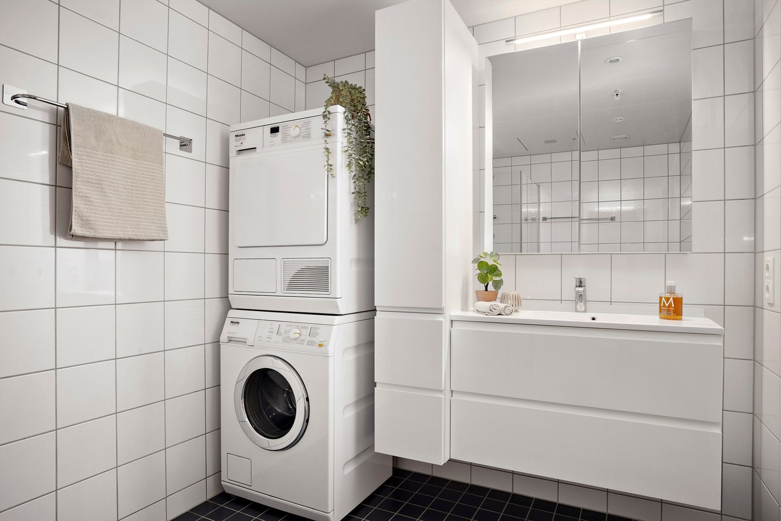 Fra gangen er det inngang til leilighetens bad/vaskerom. Badet er i tidløs stil med flislagte vegger og gulv. I gulvet er det varmekabler som reguleres etter ønske og behov. Galleribilde