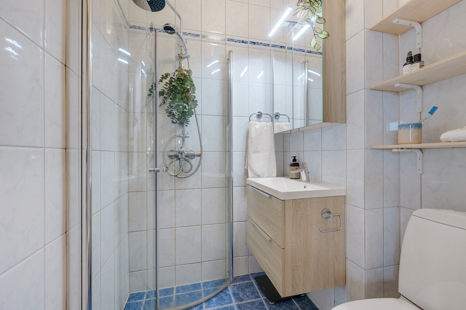 Badet inneholder vegghengt servantskap med skuffer og heldekkende servant fra 2020, speilskap, wc og dusjhjørne med svingdører. Galleribilde