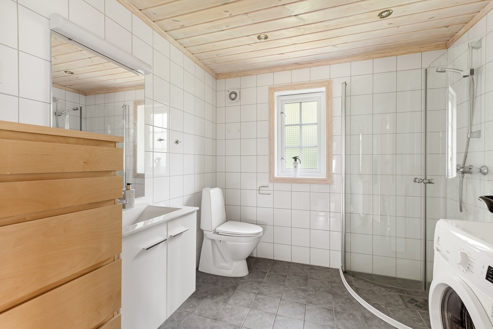 Her finner du en stilren innredning, samt et praktisk oppsett med både dusjhjørne, servant og opplegg for vaskemasin Galleribilde